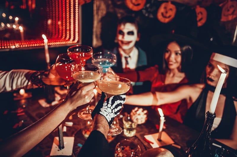 Groupe d'amis déguisés pour Halloween trinquant des coupes de champagne