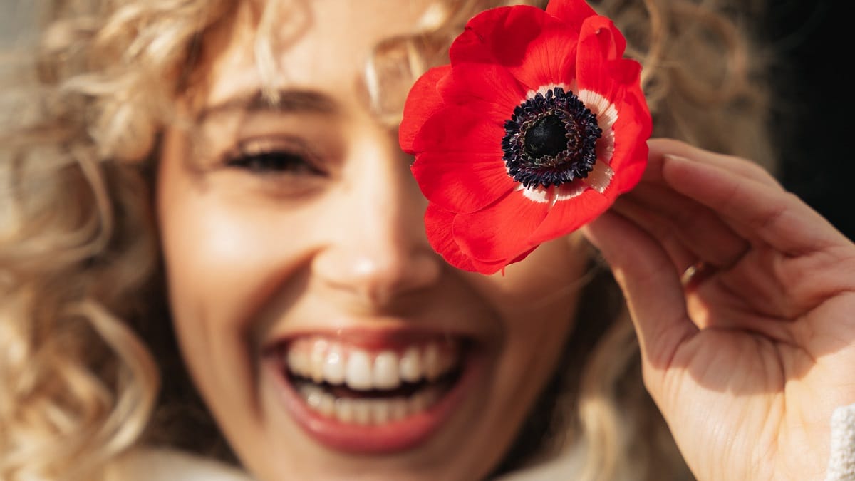 Femme souriante tenant une fleur rouge dans la main