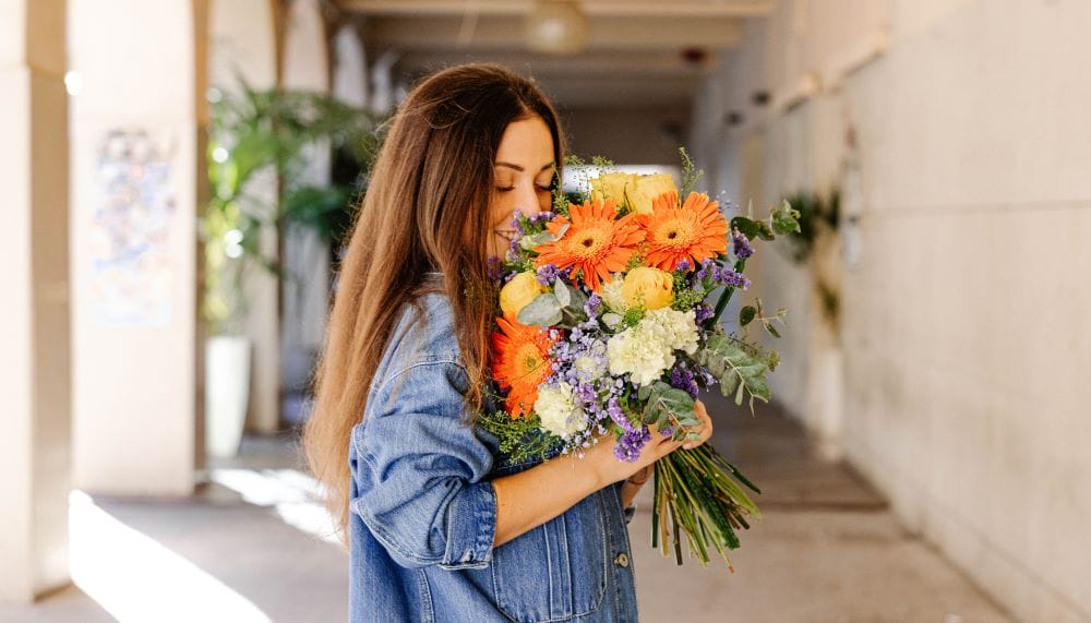 Une femme sent un bouquet de fleurs