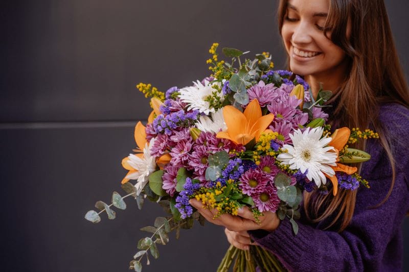 Femme souriante avec un énorme bouquet de fleurs