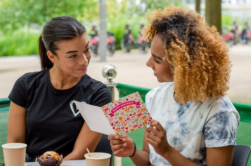 2 femmes, l'une tenant une carte joyeux anniversaire dans les mains