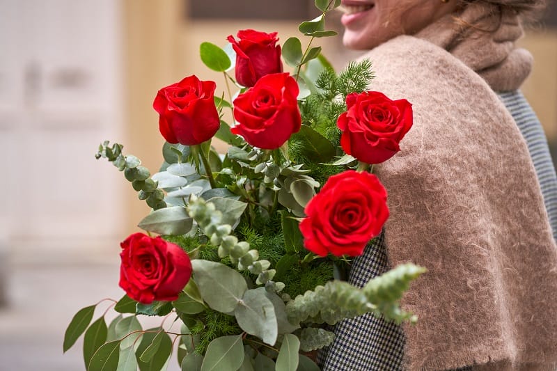 Femme de profil tenant un bouquet de roses rouges