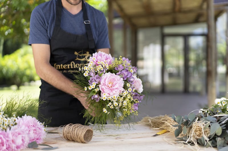 Fleuriste préparant un bouquet de fleurs rose et mauve