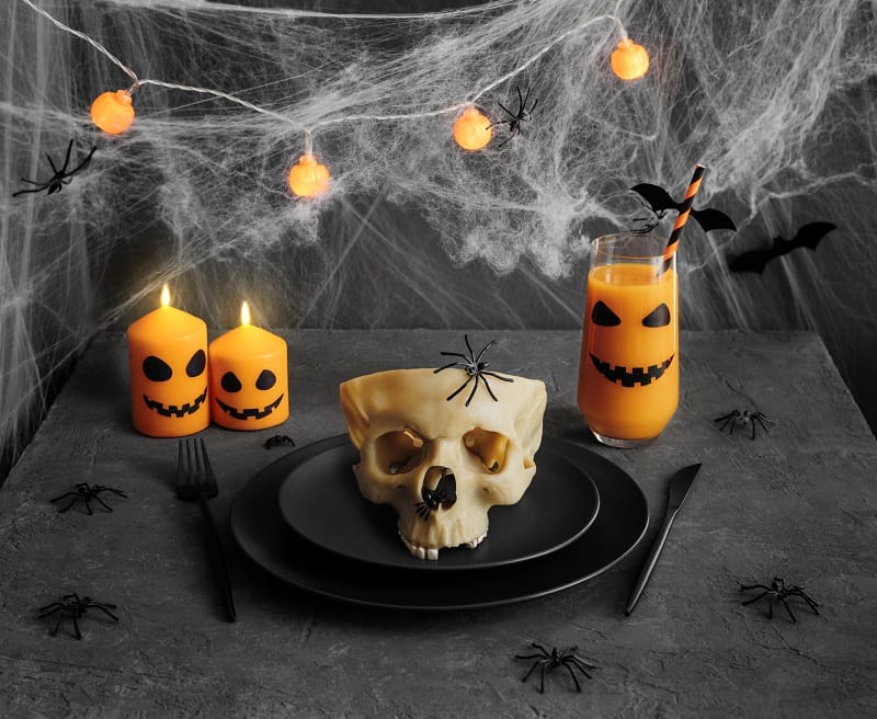 Set de table d'Halloween décoré avec des bougies, de la toile d'araignées, des araignées, un crâne...